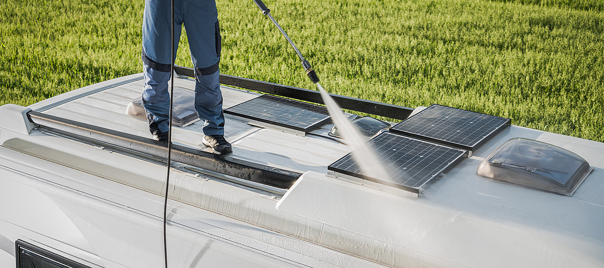 Ein Mann reinigt das Dach seines Wohnmobils bevor er es einwintert.
