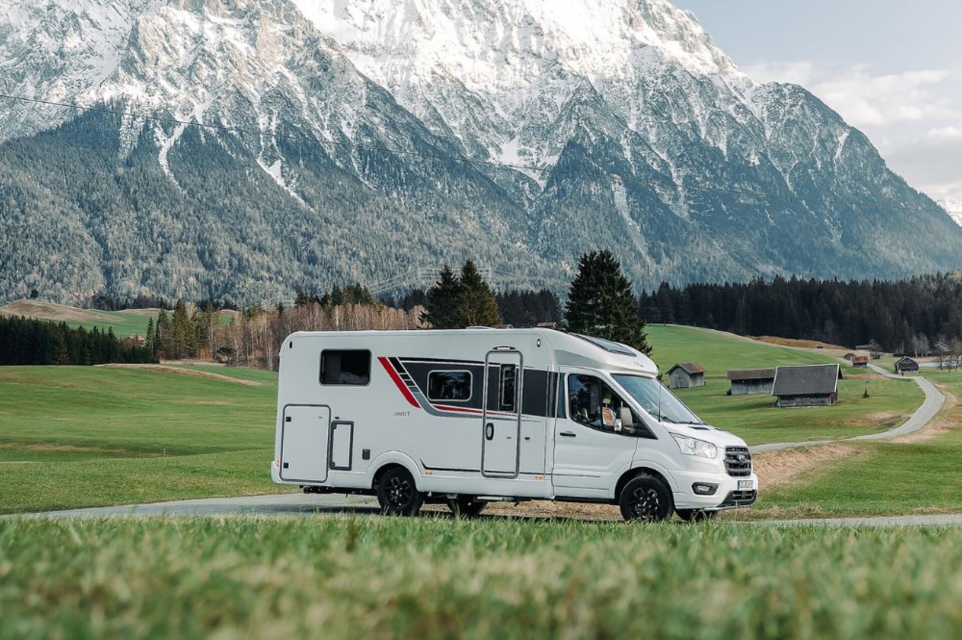 Ein Wohnmobil fährt auf einer Straße vor einem Bergpanorama