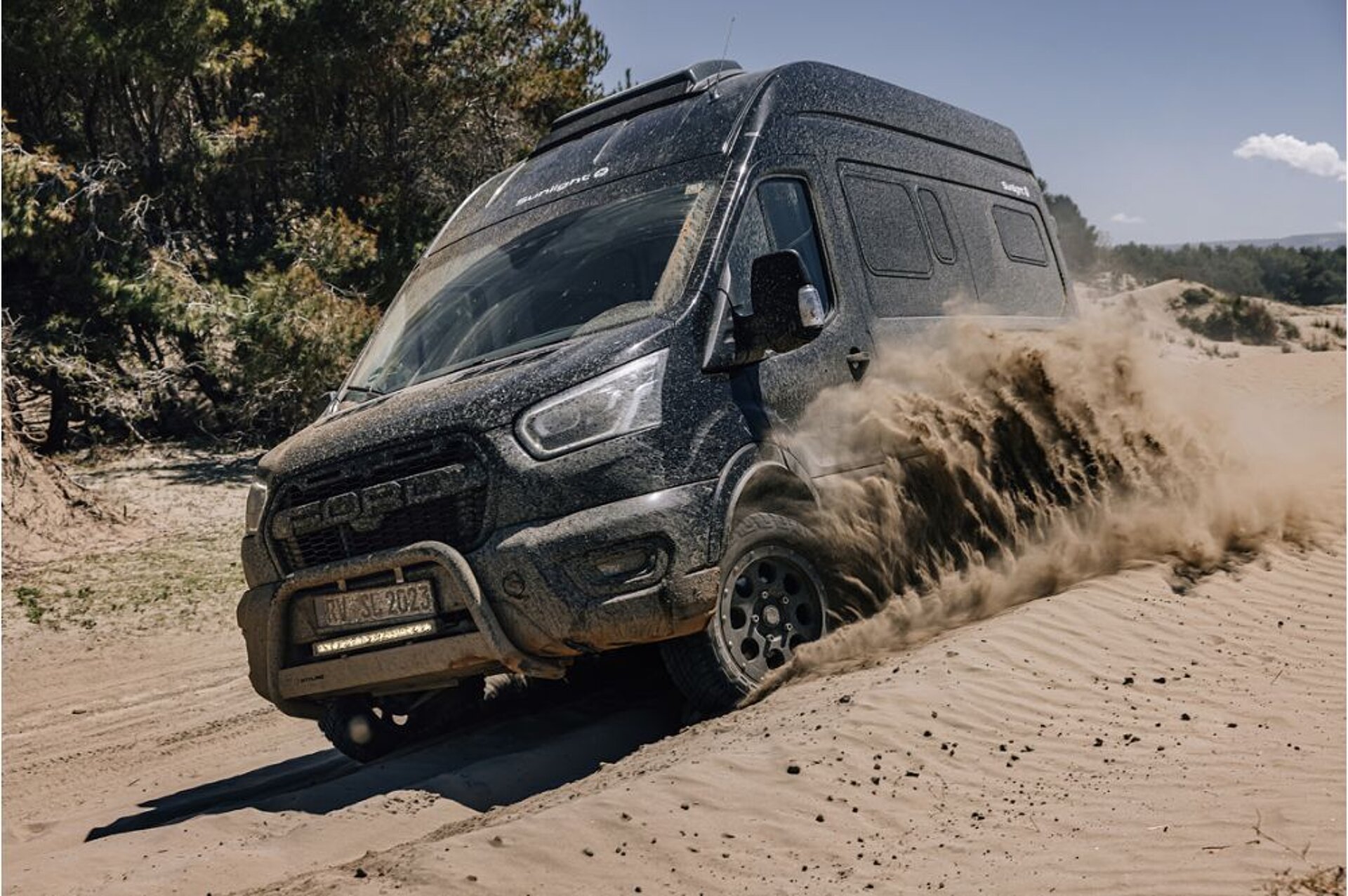 Ein Camper Van fährt auf Sand abseits der Straße.