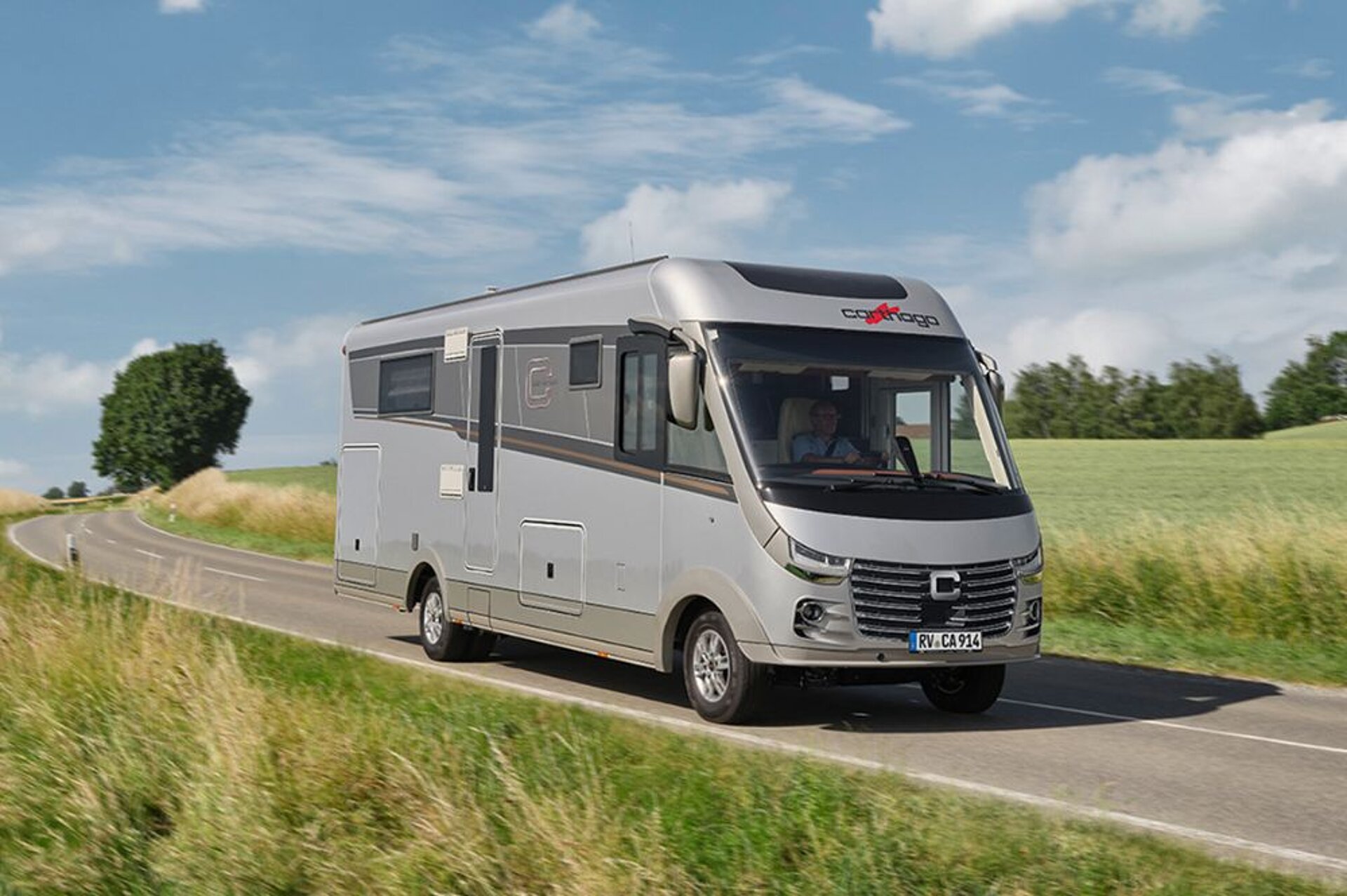 Ein Reisemobil fährt auf einer Straße zwischen zwei Wiesen entlang