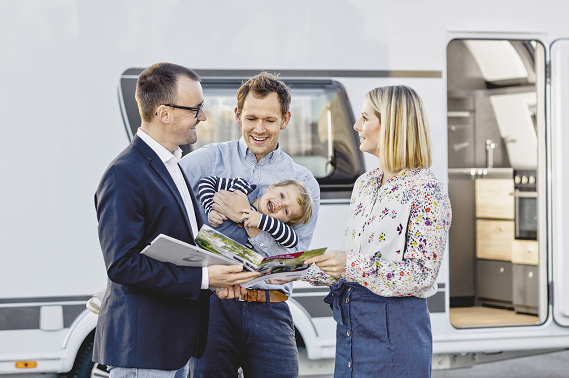 Bei Dethleffs steht die Familie immer im Mittelpunkt – seit 1931. Eine Familie mit Kind lässt sich von einem Berater ein Dethleffs Wohnmobil zeigen.