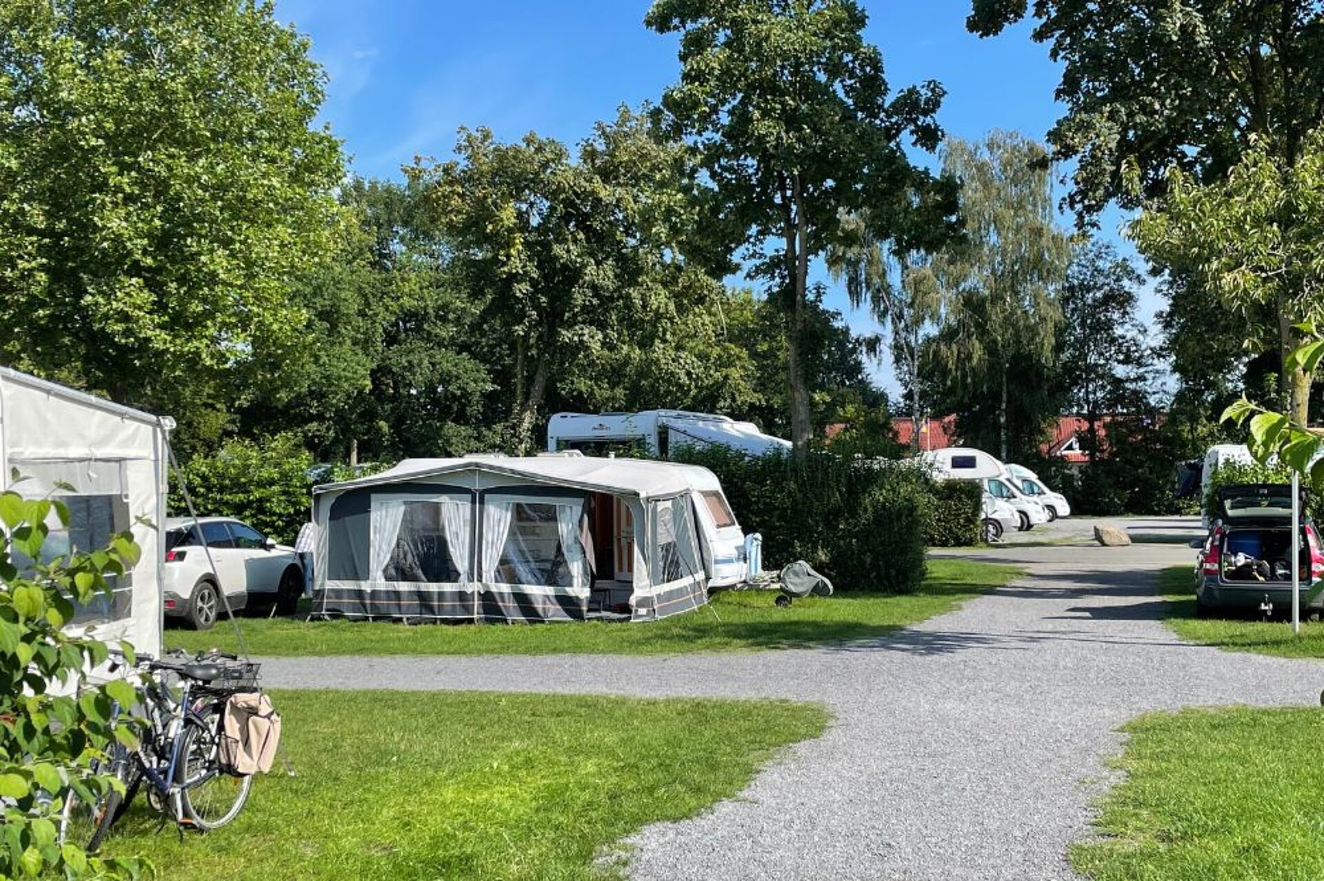 Der Stellplatz auf einem Campingplatz mit einem Wohnwagen mit Vorzelt und Wege davor