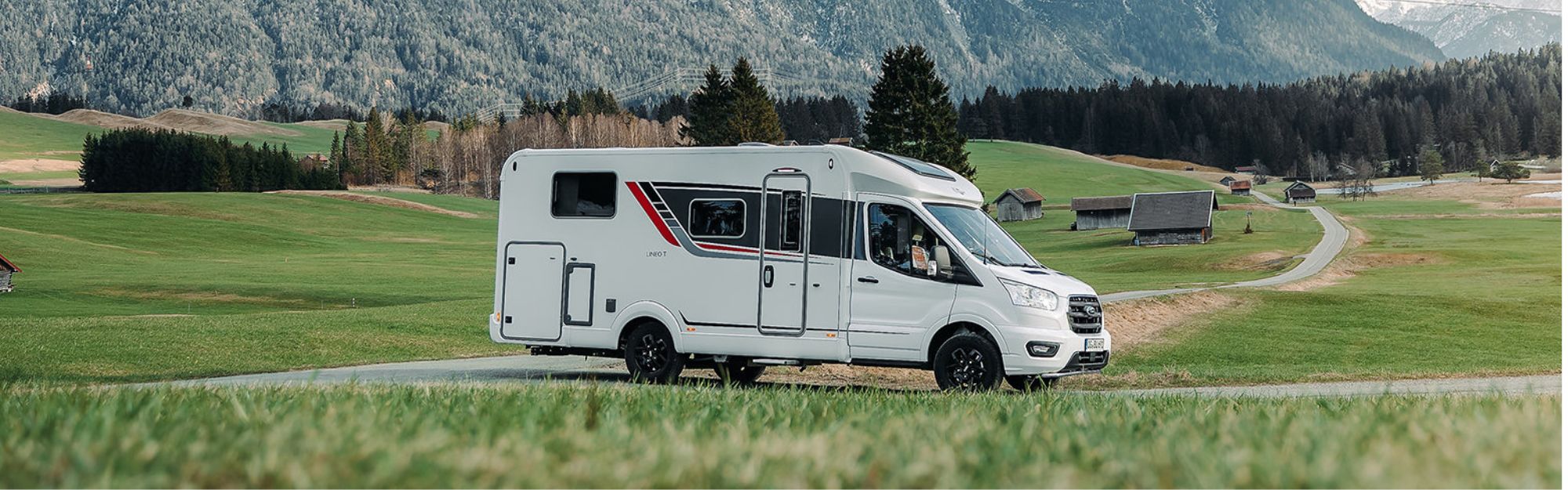 Ein Wohnmobil fährt auf einer Straße vor einem Bergpanorama